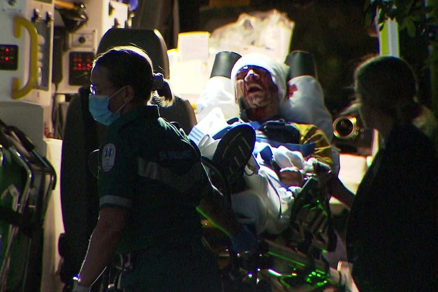 A man in an ambulance with his head bandaged.