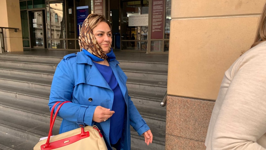 Naghmeh Mostafei, in a blue coat and patterned brown scarf, leaves court.