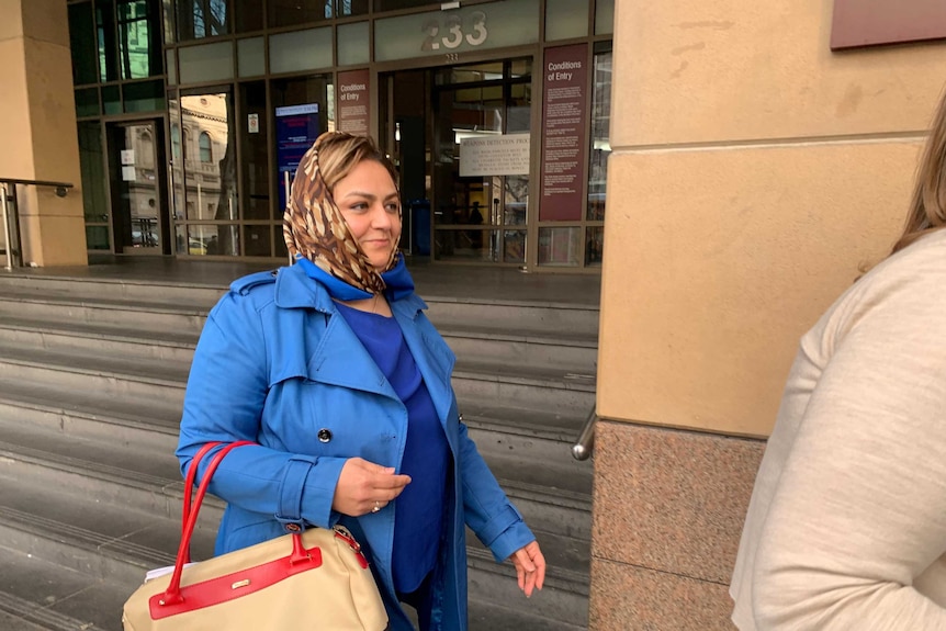 Naghmeh Mostafei, in a blue coat and patterned brown scarf, leaves court.