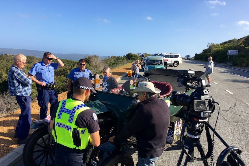 Car enthusiasts and passers by, including local police, greet the 1915 Ford Model T