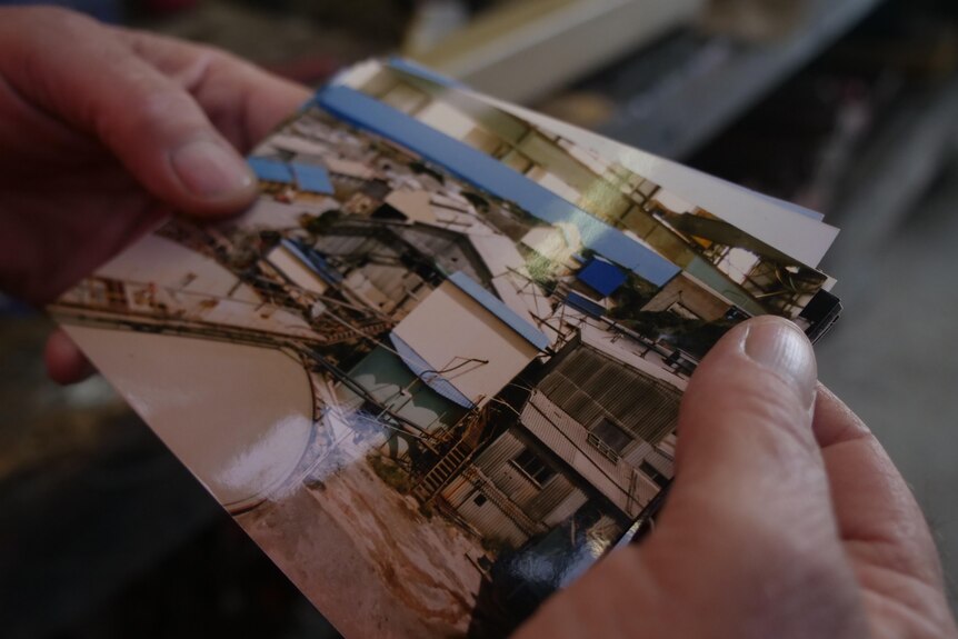 Hands holding a photo of mining infrastructure.