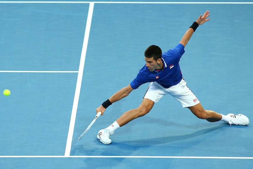 Novak Djokovic slides for a ball on a hardcourt.