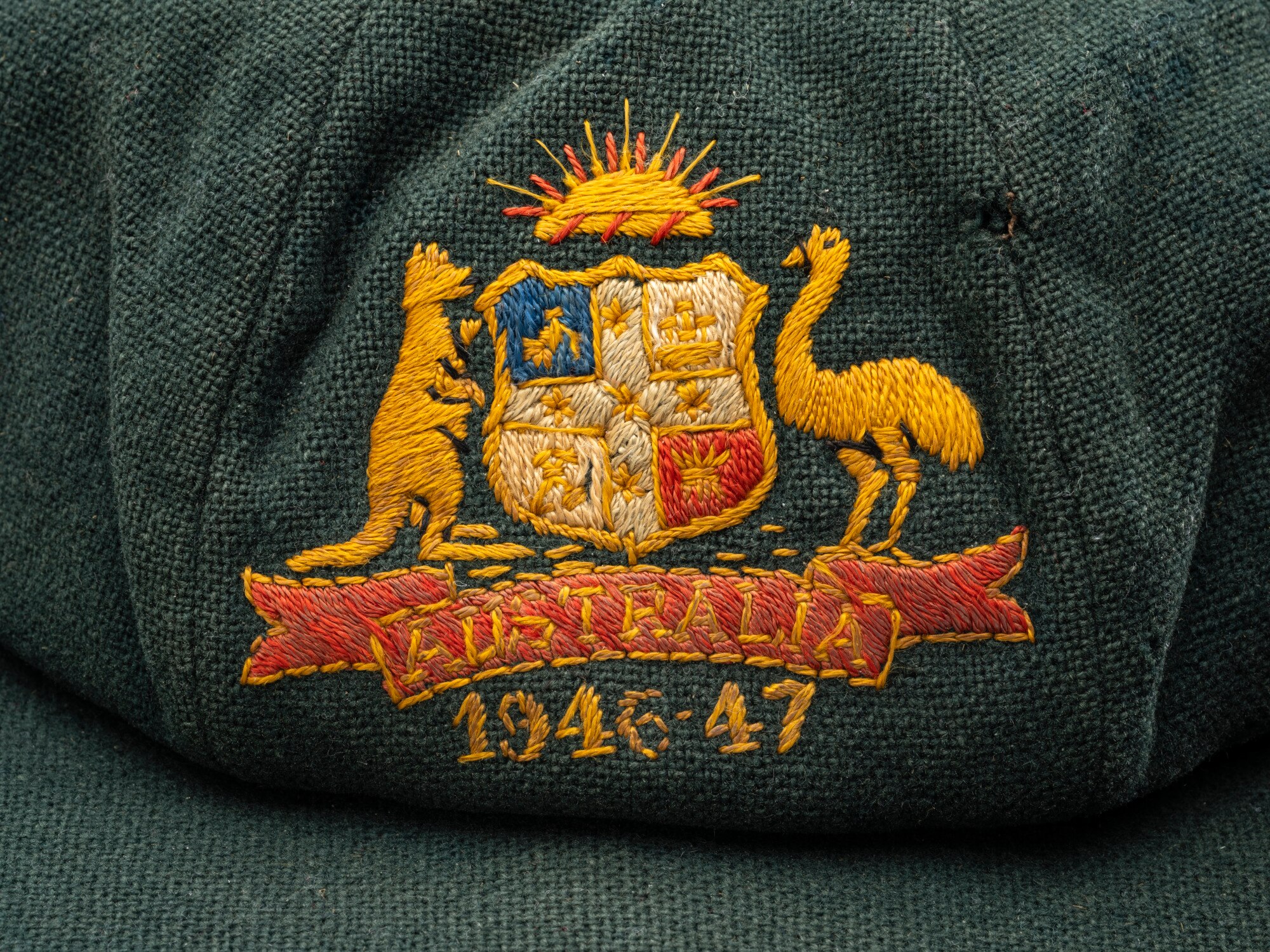 Close-up of the crest on a baggy green cricket cap with the years 1946-47 embroidered on the front.