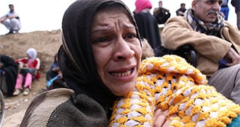 A woman holding a baby cries.