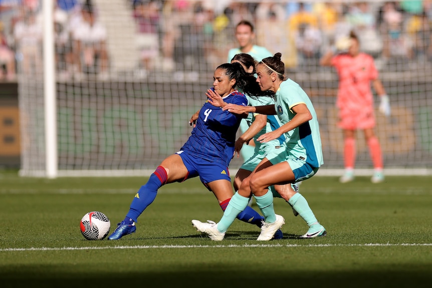 Philippines player Jaclyn Sawicki is outstretched trying to kick the ball, with Australia's Caitlin Foord next to her.