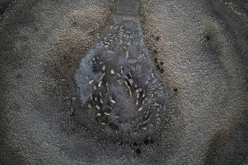 An aerial shot of dozens of rounded stones rising up out of a dried lakebed. 