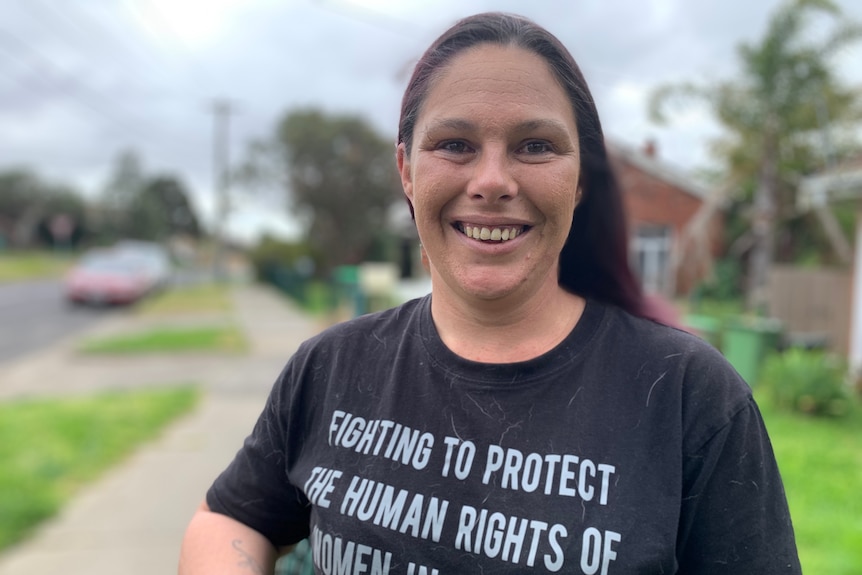 Woman standing looking at camera smiling outside her public housing  