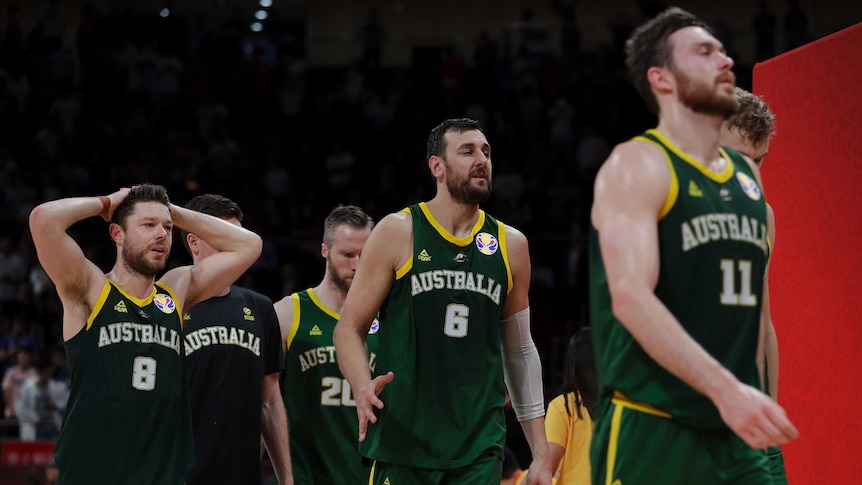 Dejected basketball players walk off the court after losing.