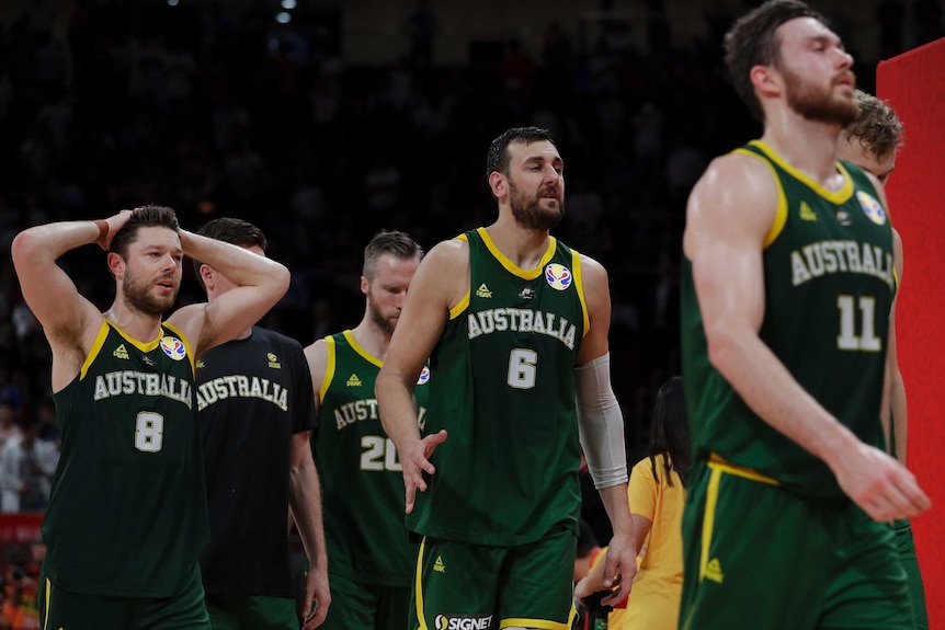 Dejected basketball players walk off the court after losing.