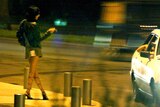 A car stops next to a prostitute standing on a street corner on the French Riviera.