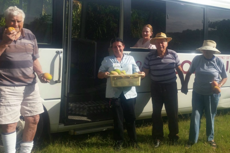 People smiling at the camera, smiling at the camera, standing by a community bus.