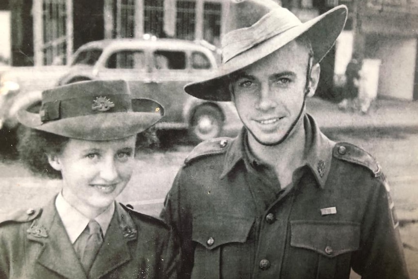 A brown photograph of a young lady and young man in army uniforms.