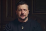 Close up of Ukrainian President speaking to camera wearing black shirt with Ukraine's trident symbol.