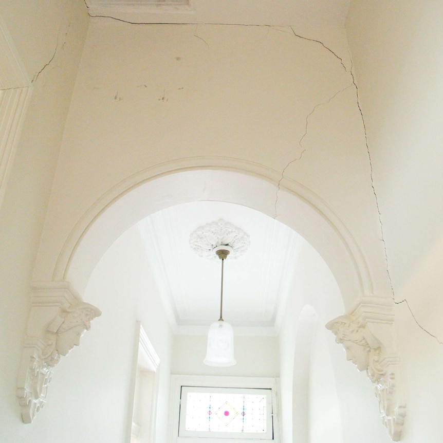 Photo showing multiple long cracks in a house's hallway.