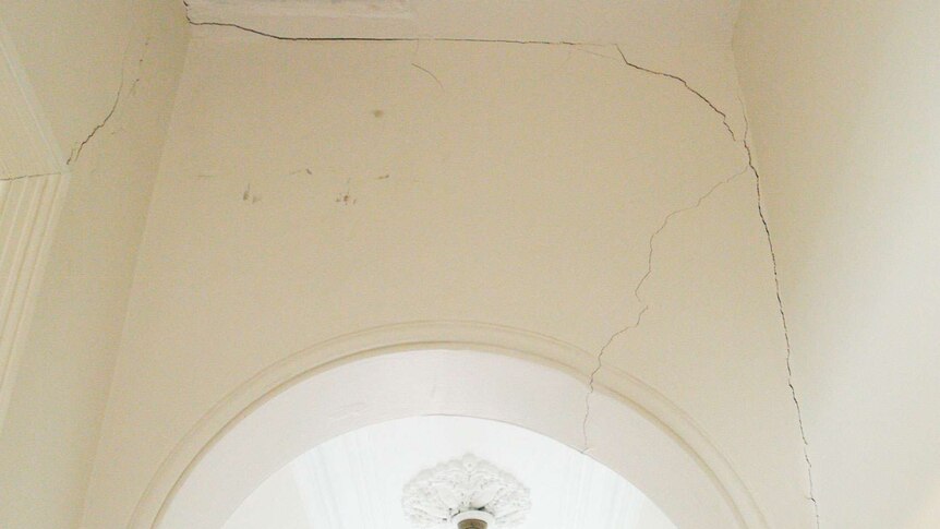 Photo showing multiple long cracks in a house's hallway.