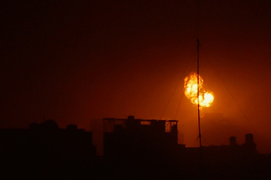 An explosion lights up the night sky red above Khan Younis in the southern Gaza Strip.
