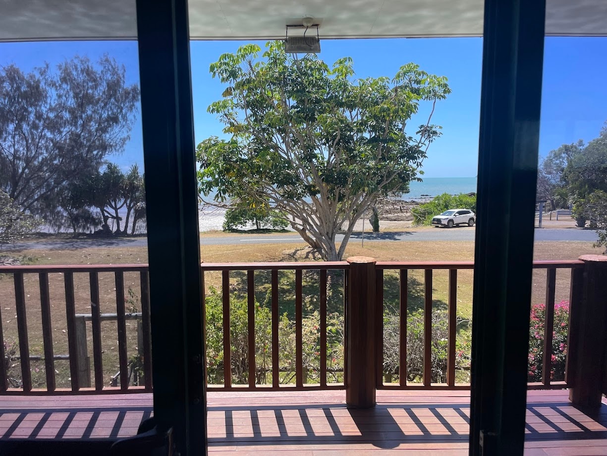 Beach with trees in the foreground taken from a doorway. 