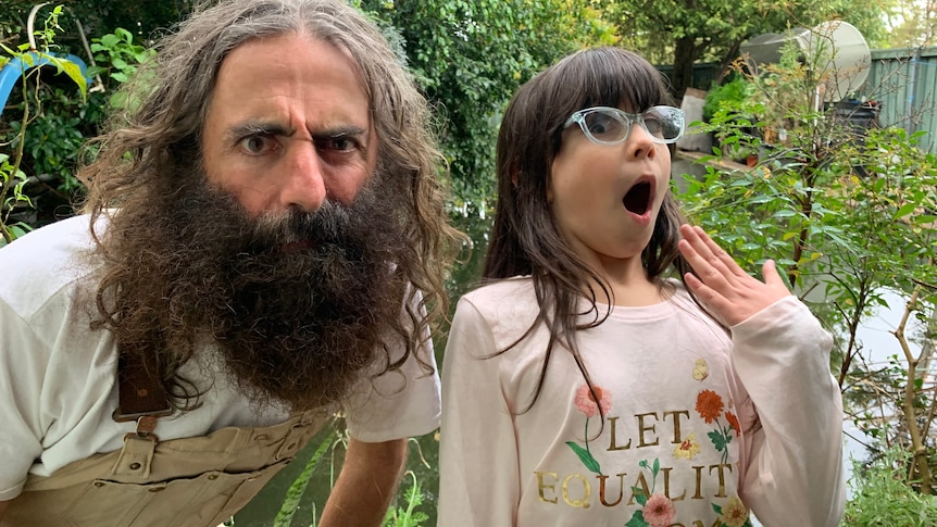 Image of a bearded Costa, from Gardening Australia, and a young girl with glasses, pulling faces together in the garden.