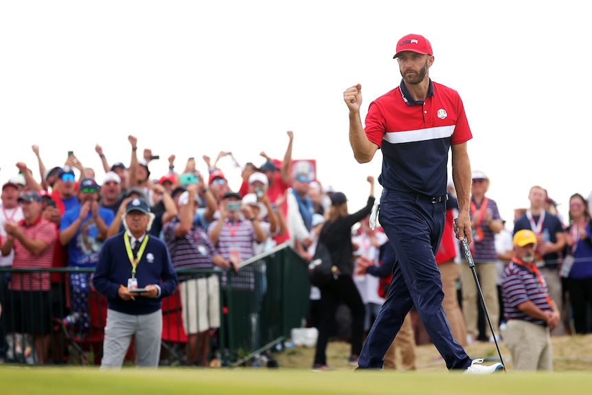 Dustin Johnson clenches his fist as supporters cheer and throw their hands up behind him