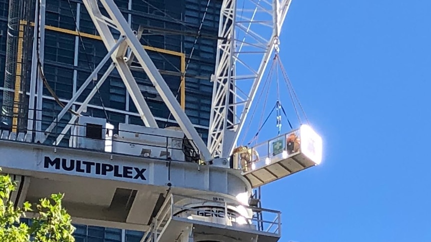 A paramedic is hoisted up to the crane platform via another platform.