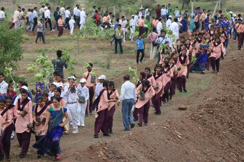 Indian people carry trees to plant