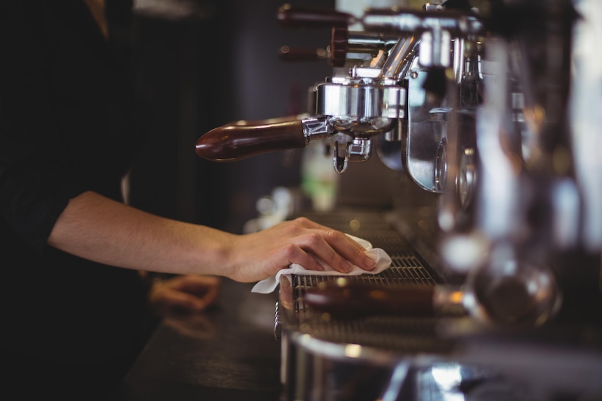 A barista wiping down a coffee machine in a cafe