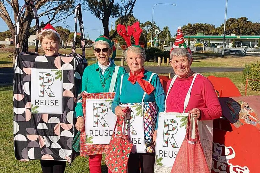 Four older women dressed in Christmas bag costumes with the word 'Reuse' on them.