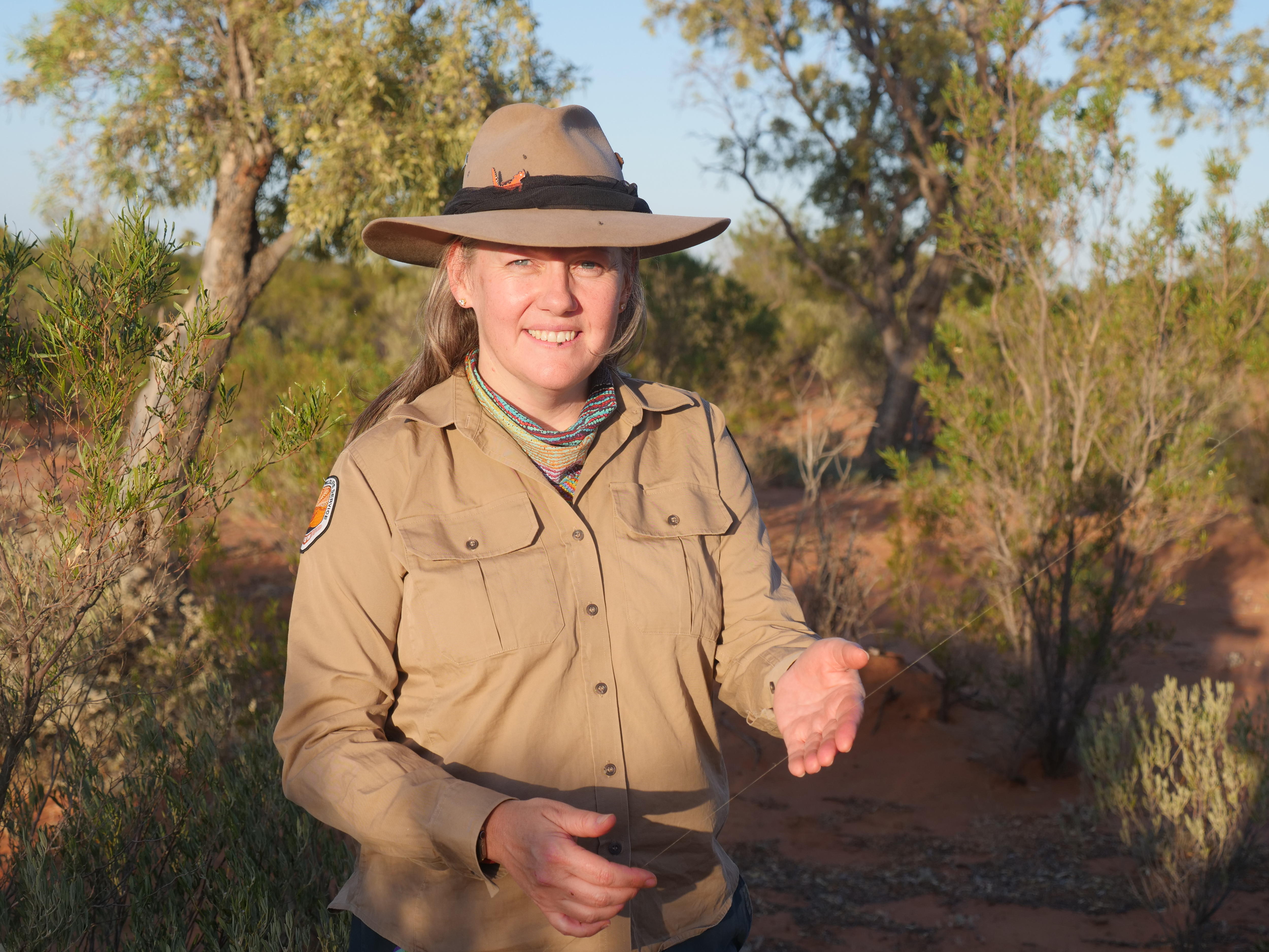 Mujer con camisa caqui de manga larga sostiene telaraña de orbe dorado