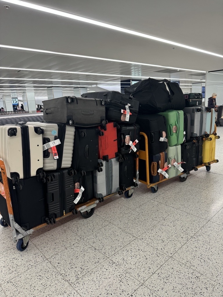 An image of 25 suitcases stacked on top of each other at an airport.