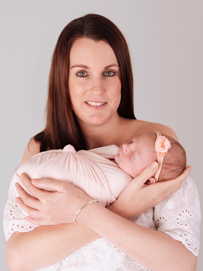 Lauren O'Neill holds her daughter Daisy to her chest and looks at the camera.