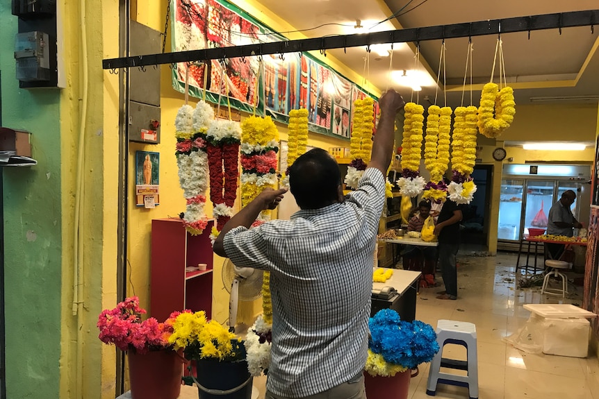 Un uomo prepara fiori per la vendita vicino a un tempio indù a Kuala Lumpur