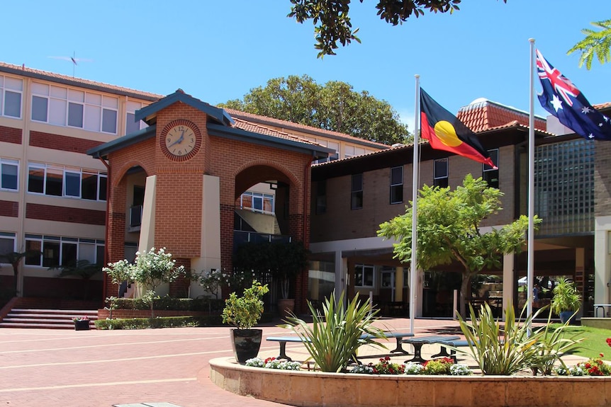 The front entrance of a school with flags flying outside.