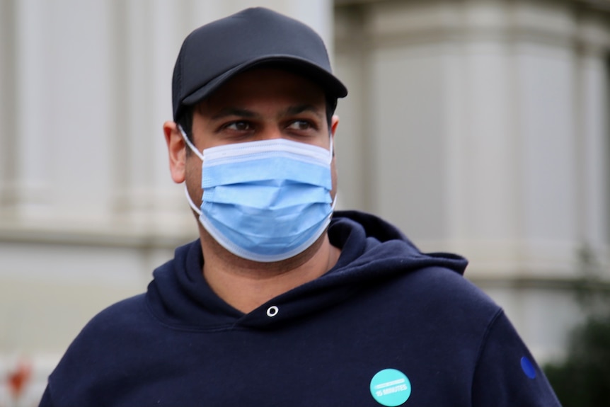 A man in a hat and a surgical mask.