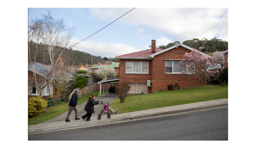 Two people walk up a footpath on a steep hill.