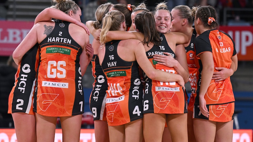 A group of GWS Giants players hug each other on the court