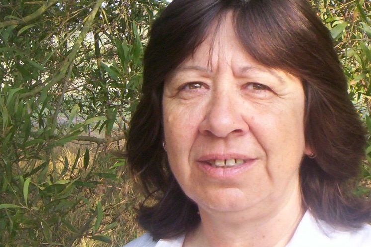 A woman stands in front of a garden.