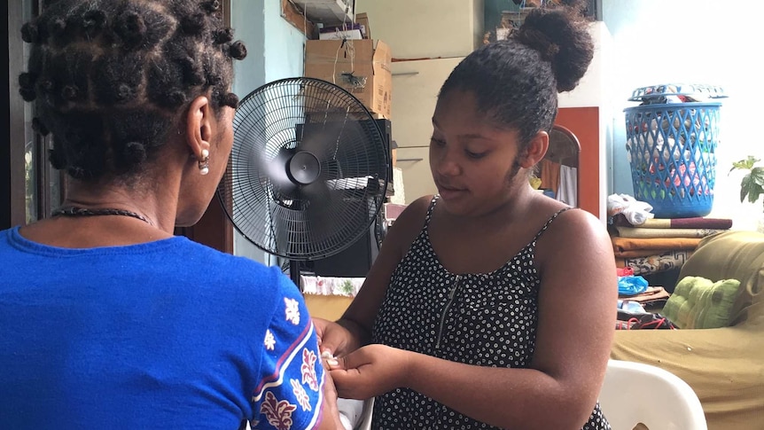 Pregnant 16-year-old Adryelle de Olivera Nunes Santos gives a woman a manicure.