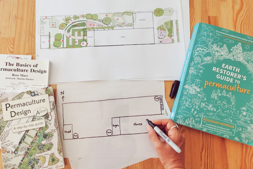 books and drawings sit on a wooden table