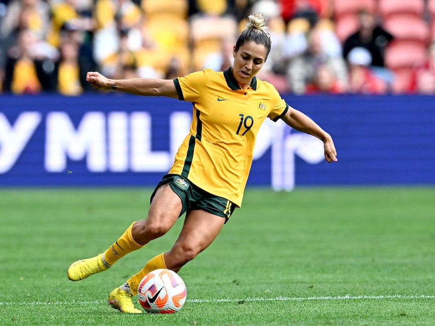 A woman soccer player wearing yellow and green dribbles during a game