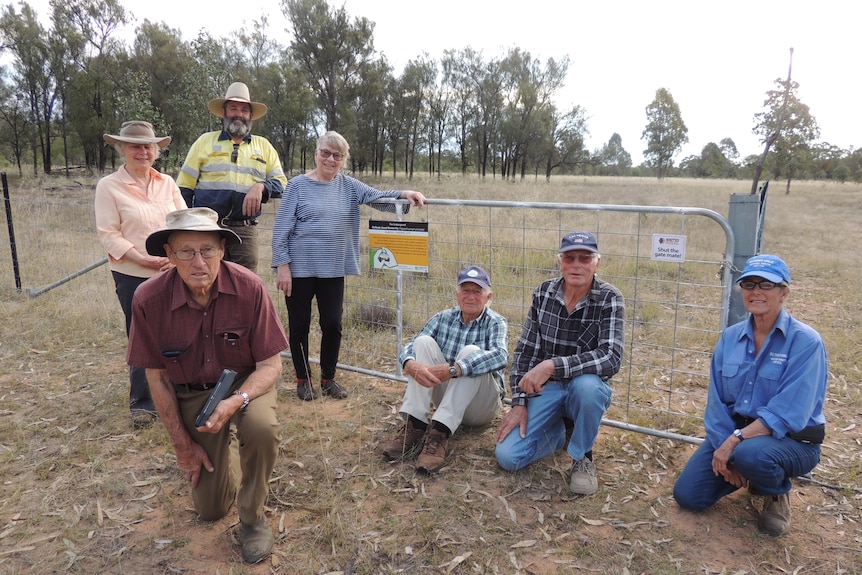 A group of people in front of a metal gate and fence.