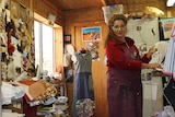 A woman with curly red hair stands in a sewing room.