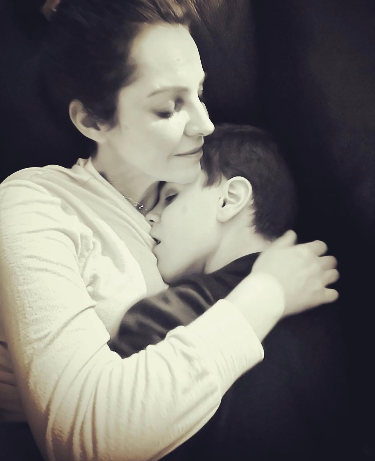 Un hombre abraza a su hijo que está sentado en un sofá.