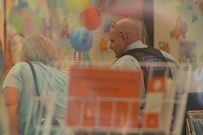An ACT police officer conducting investigations at the Belconnen Library in September 2013.
