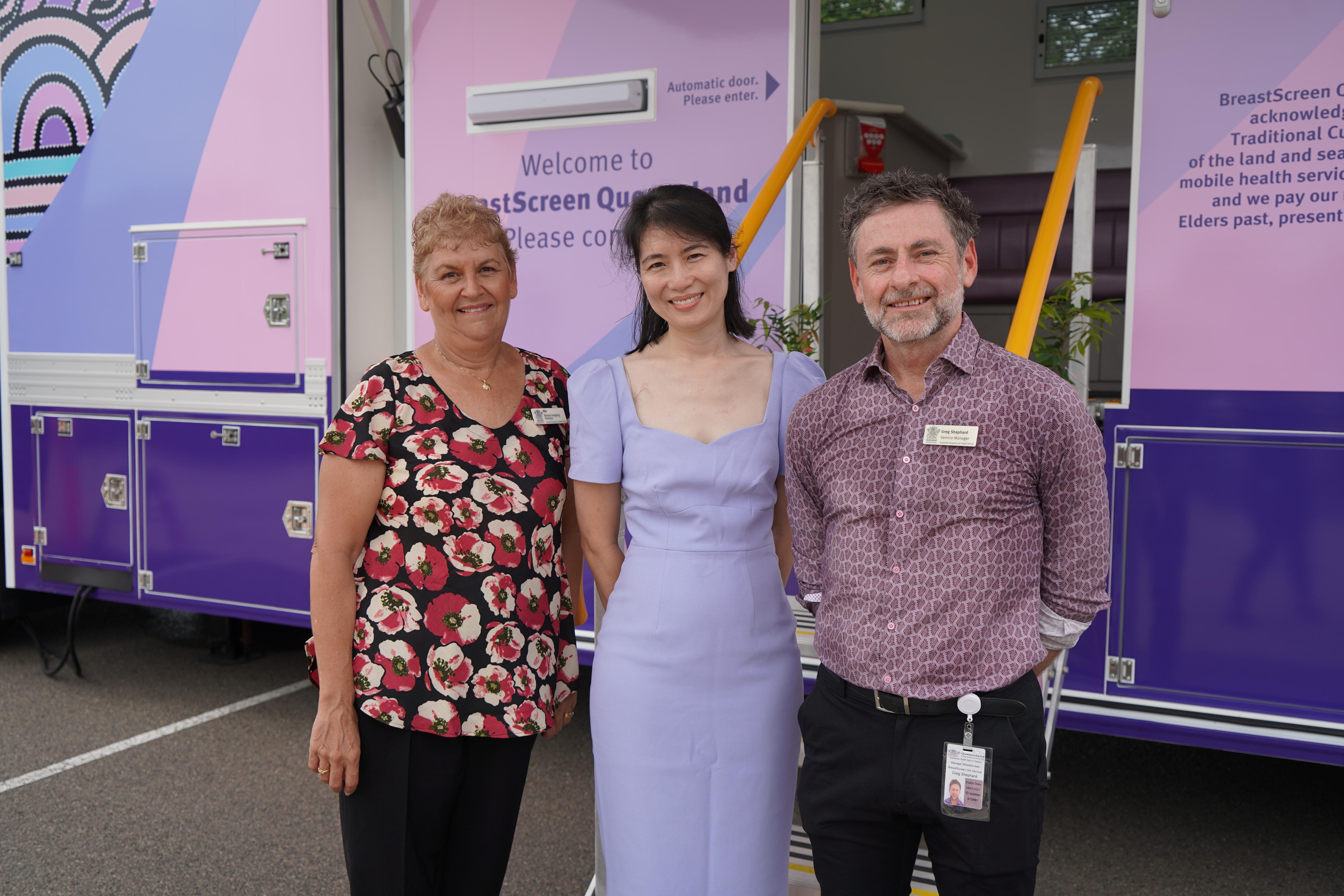 Dr April Miu standing in between two people, in front of a BreastScreen van in Townsvilles, Queensland.