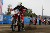 motorbikes line up at start line of Finke desert race, bike in front has just taken off 