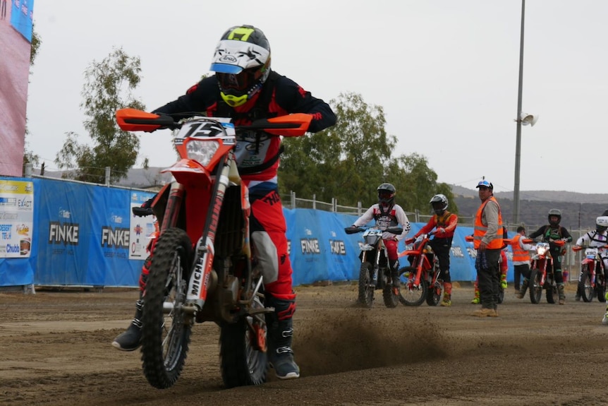 Motorbikes line up at start line of a desert race.