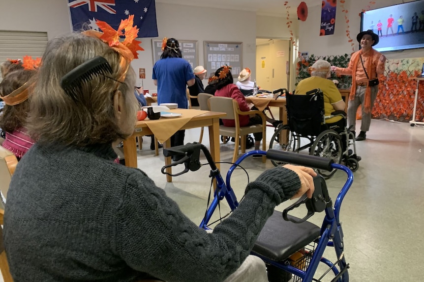 Elderly people sit in chairs.