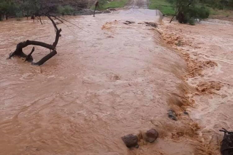 Brown rushing water over a road.