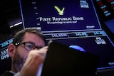 a trader wearing glasses works at the post where First Republic stock is traded at the NYSE