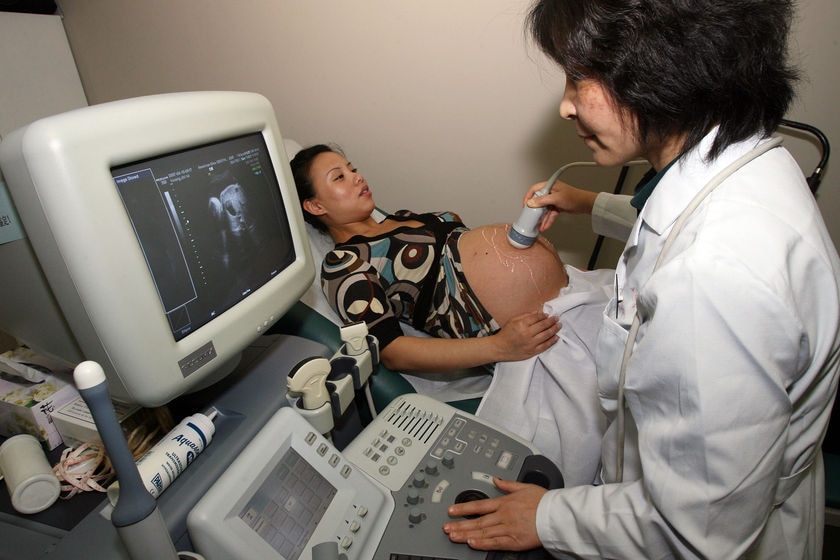 Medical staff conduct ultrasound tests on a pregnant woman